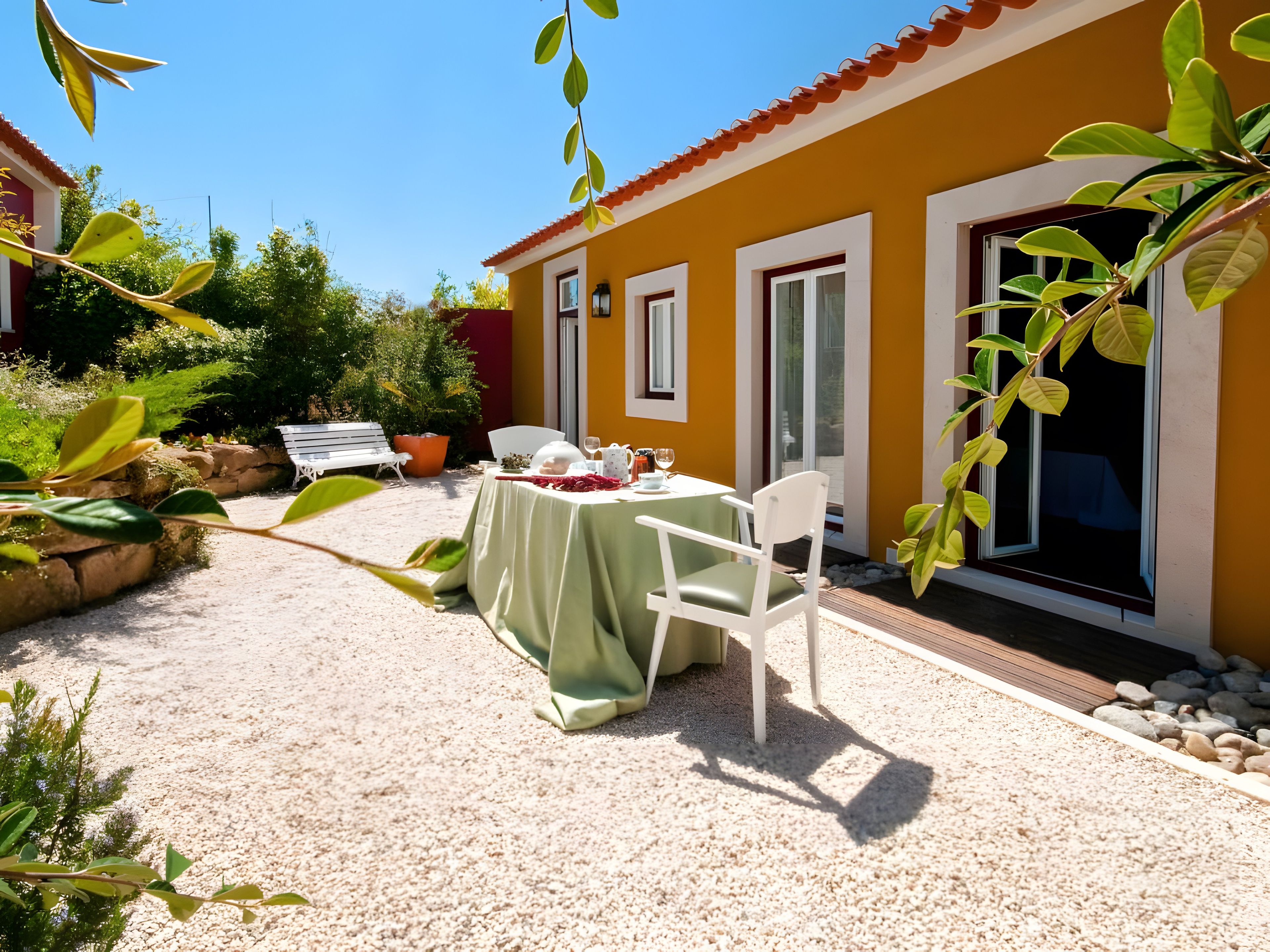 Une terrasse avec une table dressée pour deux personnes, une chaise blanche et un banc.
