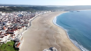 A coastal cityscape with a wide sandy beach, a clear blue sea, and a dense cluster of buildings with red-tiled roofs. - Country House 'D’Olívia Lovely Homes -Casa Olívia' with Shared Garden, Wi-Fi and Air Conditioning (Cela)