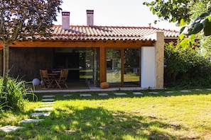 Een huis met een pannendak, een overdekt terras en een gazon met stapstenen.