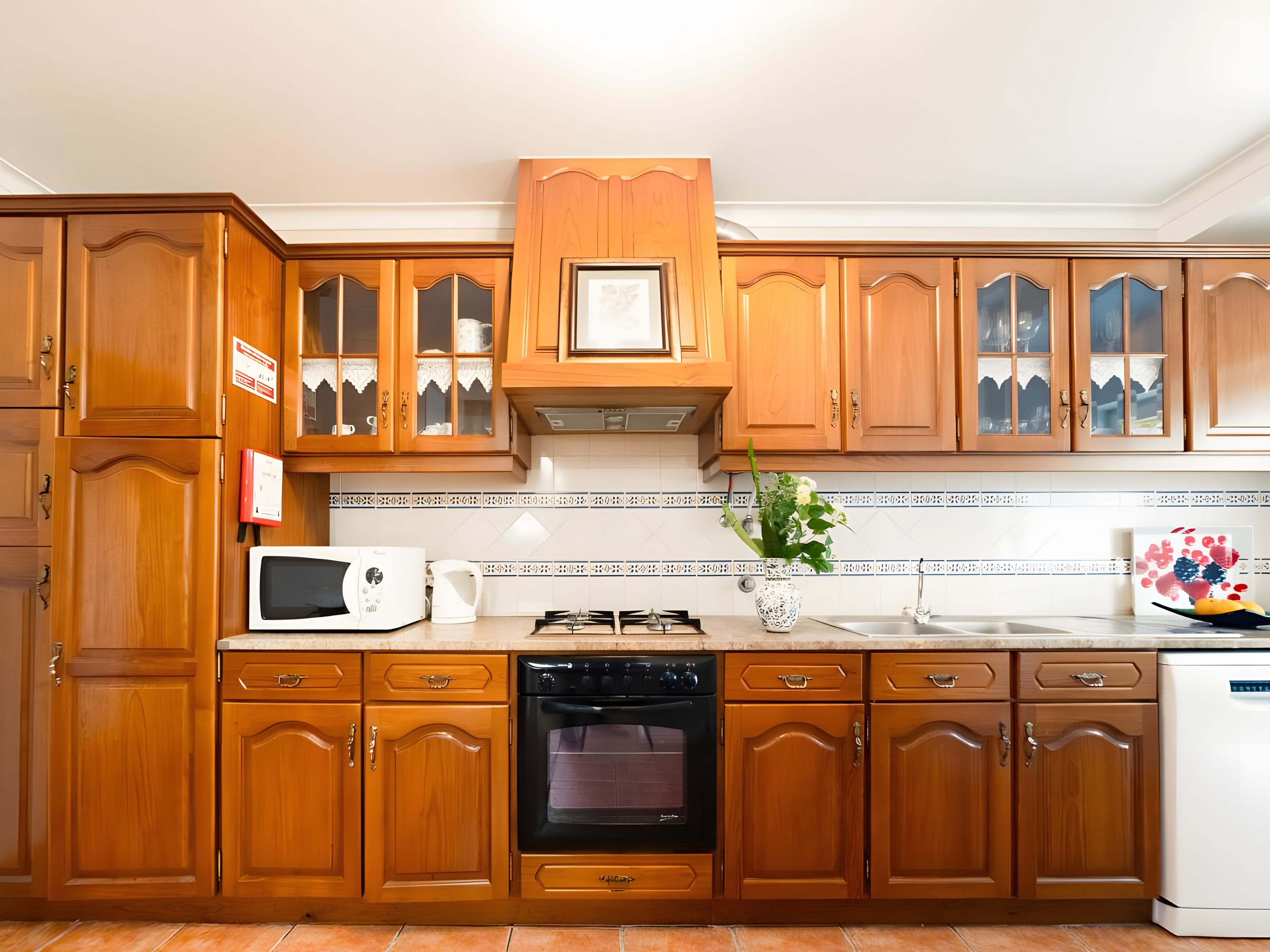 A kitchen with wooden cabinets, a microwave, an oven, and a sink.
