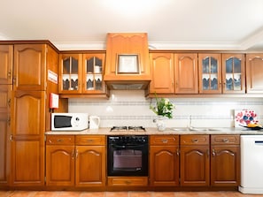 A kitchen with wooden cabinets, a microwave, an oven, and a sink. - Country House 'D’Olívia Lovely Homes -Casa Olívia' with Shared Garden, Wi-Fi and Air Conditioning (Cela)