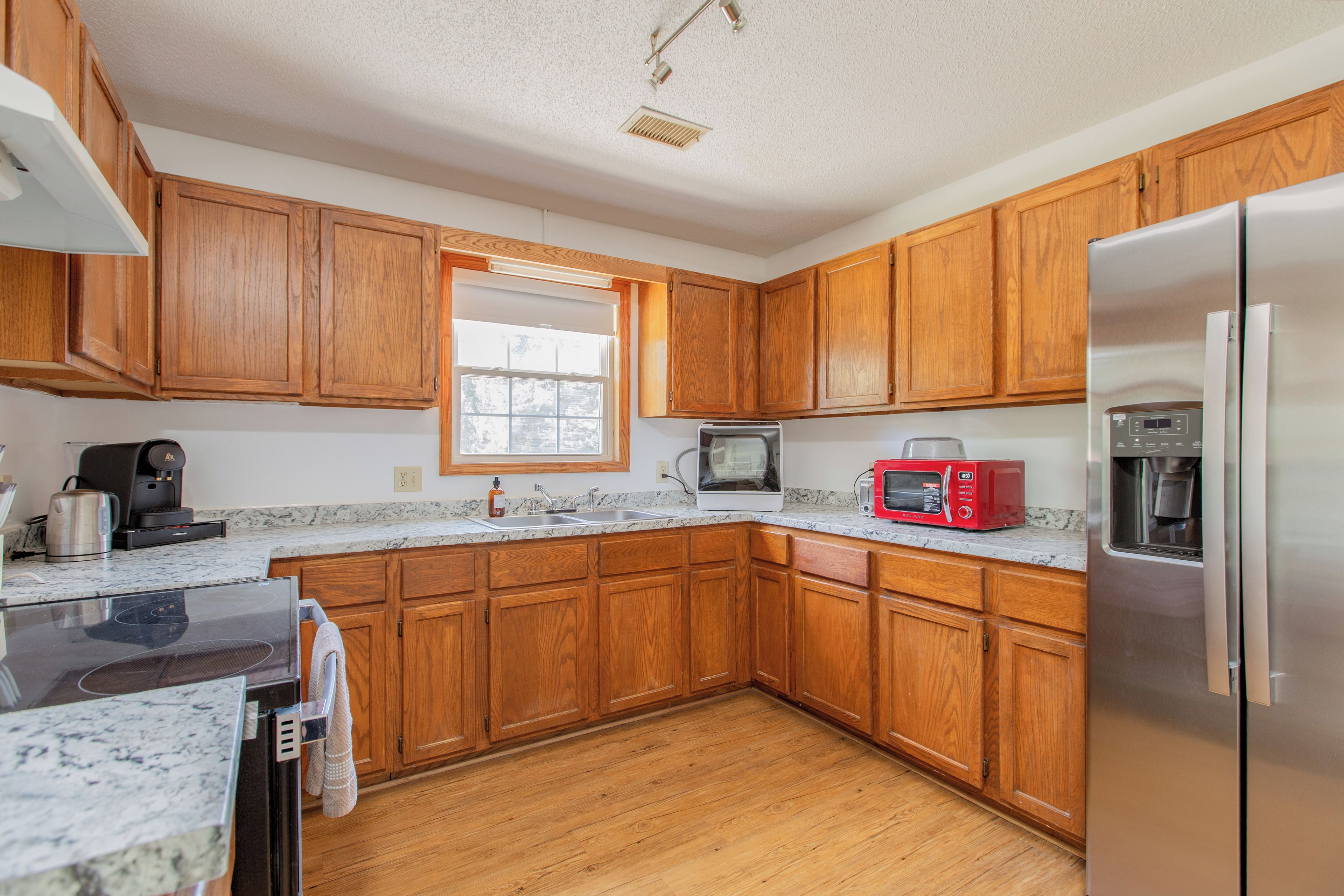 A kitchen with wooden cabinets, a stainless steel refrigerator, a microwave, and a coffee maker.
