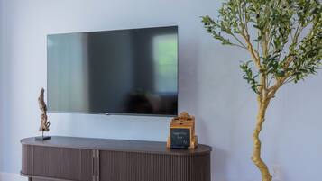 A flat-screen TV mounted on a wall above a wooden console with a suggestion box.