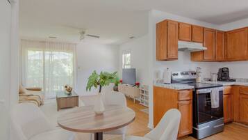 A modern kitchen with wooden cabinets, a built-in oven, and a dining area with a round table and white chairs.