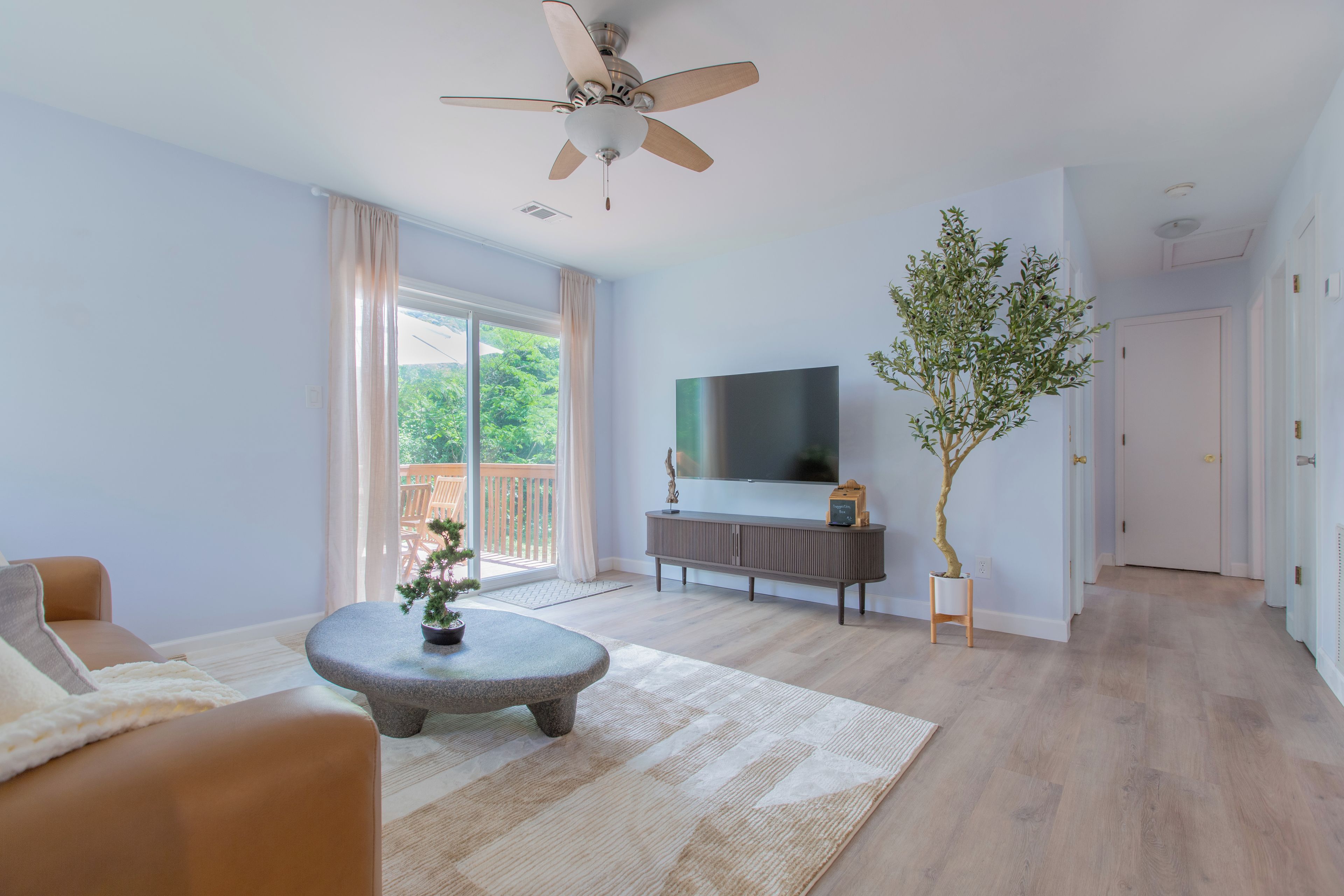 A modern living room with a stone coffee table, a sofa, a flat-screen TV, and a ceiling fan.