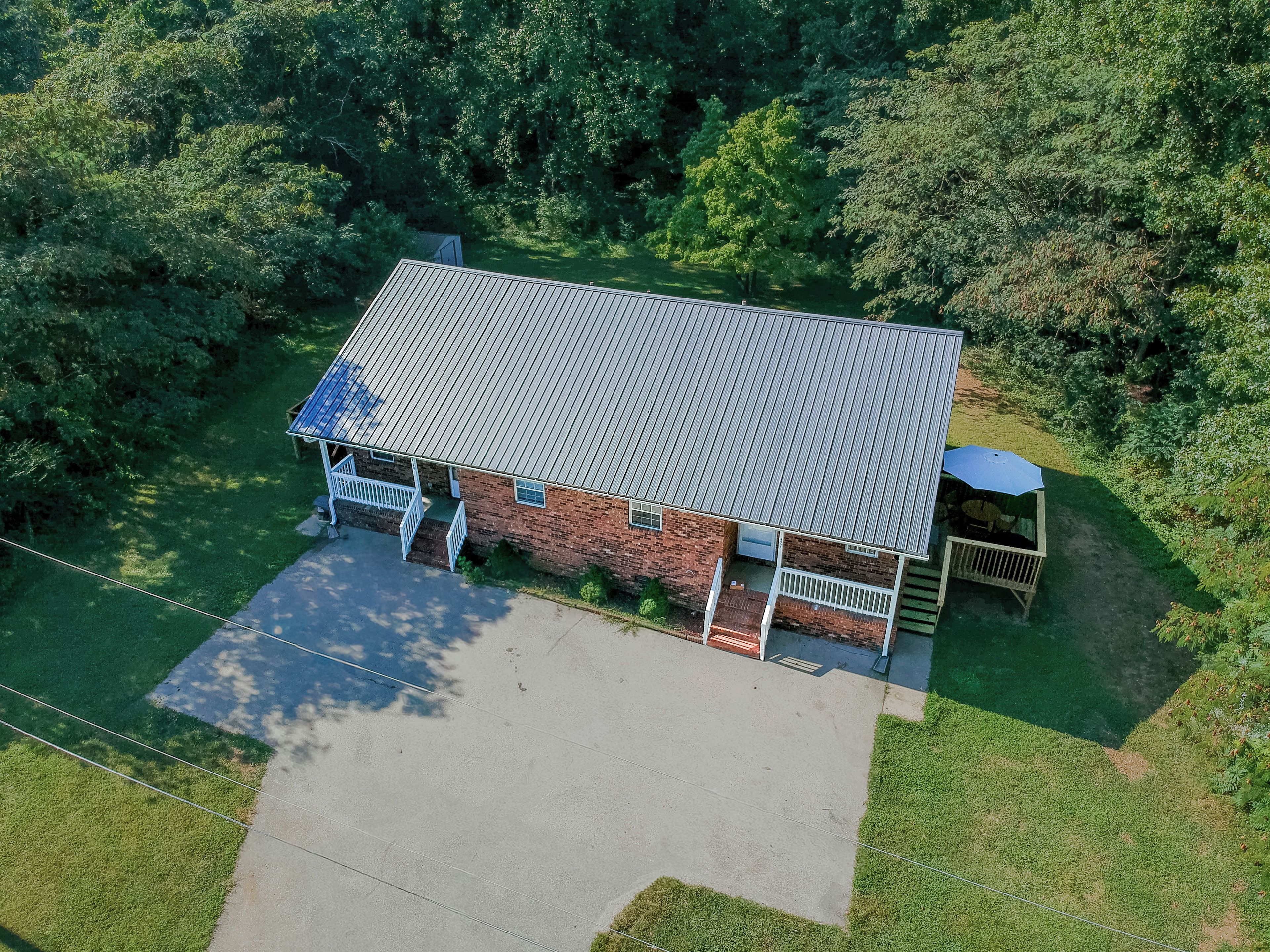 A single-story brick building with a flat roof, a covered porch, and a small attached shed.