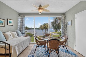 A room with a bed, a dining table with chairs, a ceiling fan, and a view of a lake. - Bay View at Sutton Place | Longboat Key | Beach Access | 30-Day Min (Longboat Key)