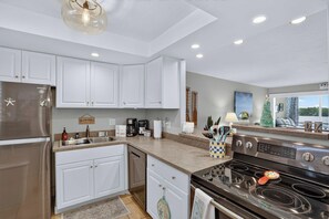 A modern kitchen with white cabinets, stainless steel appliances, and a granite countertop. - Bay View at Sutton Place | Longboat Key | Beach Access | 30-Day Min (Longboat Key)