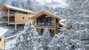 Una cabaña de madera con balcón, rodeada de árboles cubiertos de nieve.