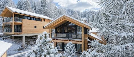 A wooden cabin with a balcony, surrounded by snow-covered trees.