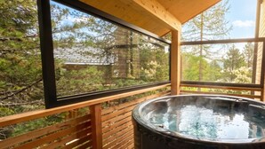 Un jacuzzi en una terraza de madera con vistas a árboles y un edificio.