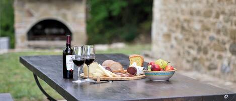 Un montaje para picnic con una botella de vino, copas, queso, pan y fruta sobre una mesa.