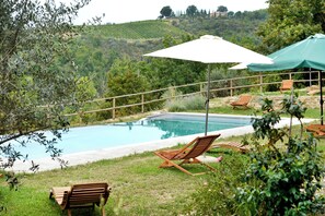 A swimming pool with lounge chairs and a pergola with a white umbrella. - Charming Italian Farmhouse with Sunset views, Ensuites & Private Infinity Pool (Umbria)