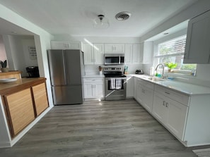 Una cocina moderna con armarios blancos, electrodomésticos de acero inoxidable y encimera de madera.
