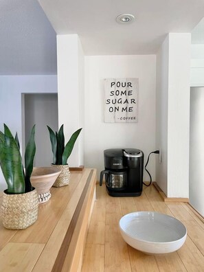 Ein modernes Interieur mit Kaffeemaschine, Topfpflanzen und einem Wandschild.