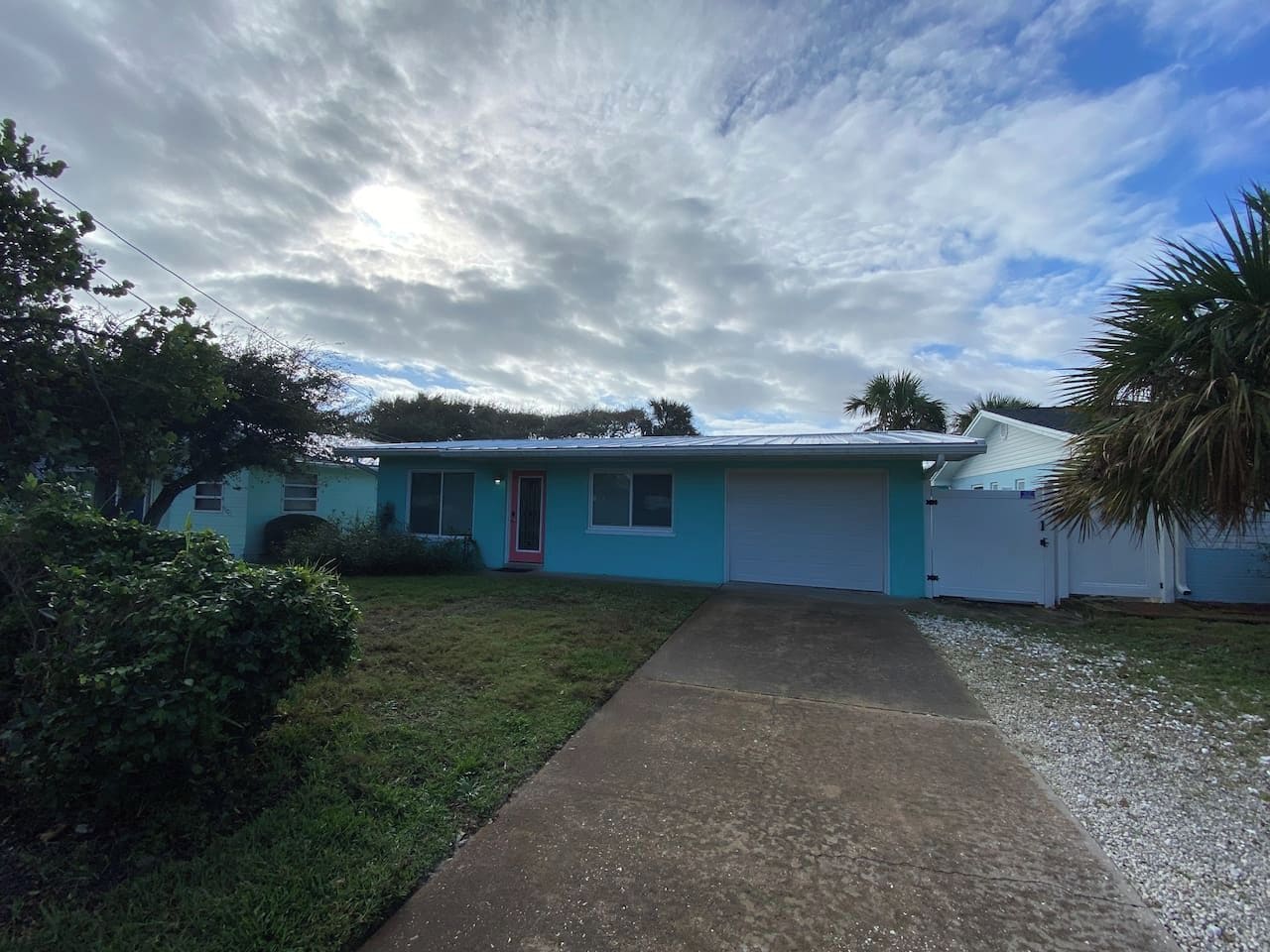 A single-story house with a garage, a front yard, and a cloudy sky.