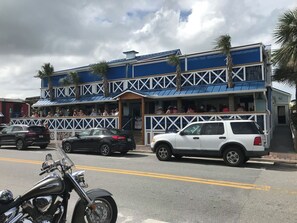 A two-story building with a blue and white facade, a balcony with white railings, and a parked motorcycle in the foreground. - Sandy Toes on Cedar - steps from the beach (New Smyrna Beach)
