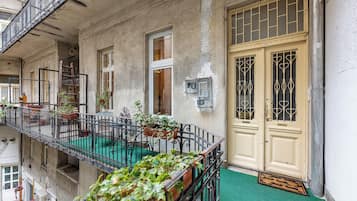 Un edificio con un balcone, piante in vaso e una porta con un cartello.