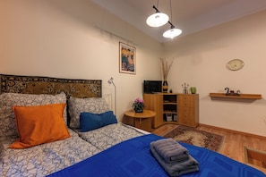 Ein Schlafzimmer mit einem Bett, einem Nachttisch, einem Fernseher und einer Wanduhr.