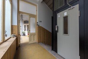 A hallway with a wooden bench, a door labeled 'IEM', and a staircase leading to an upper floor. - Delightful 1-bedroom studio in the center of vibrant Budapest just for you (Budapest)