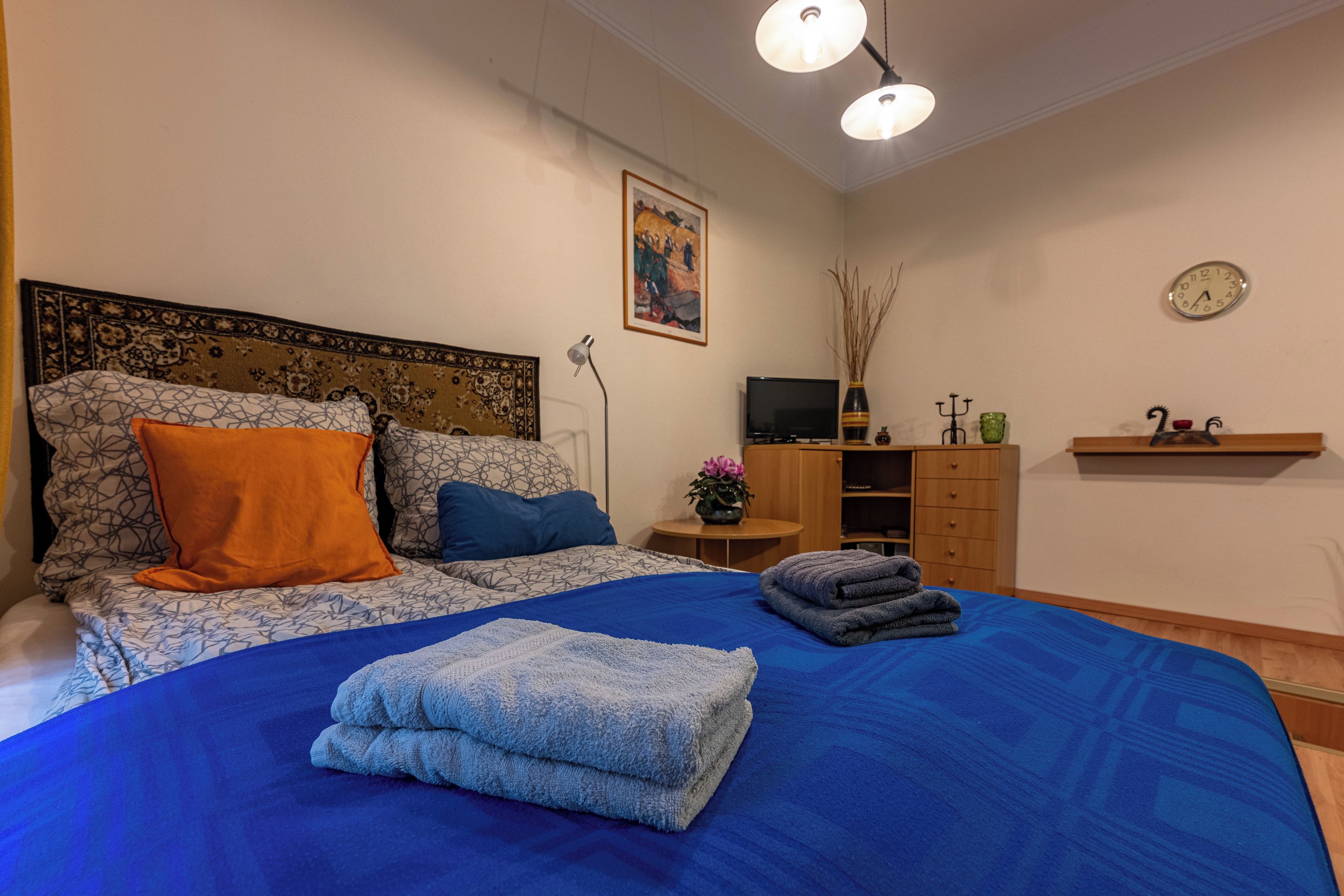 Een slaapkamer met een groot bed, een televisie, een bureau en een plank met decoratieve objecten.