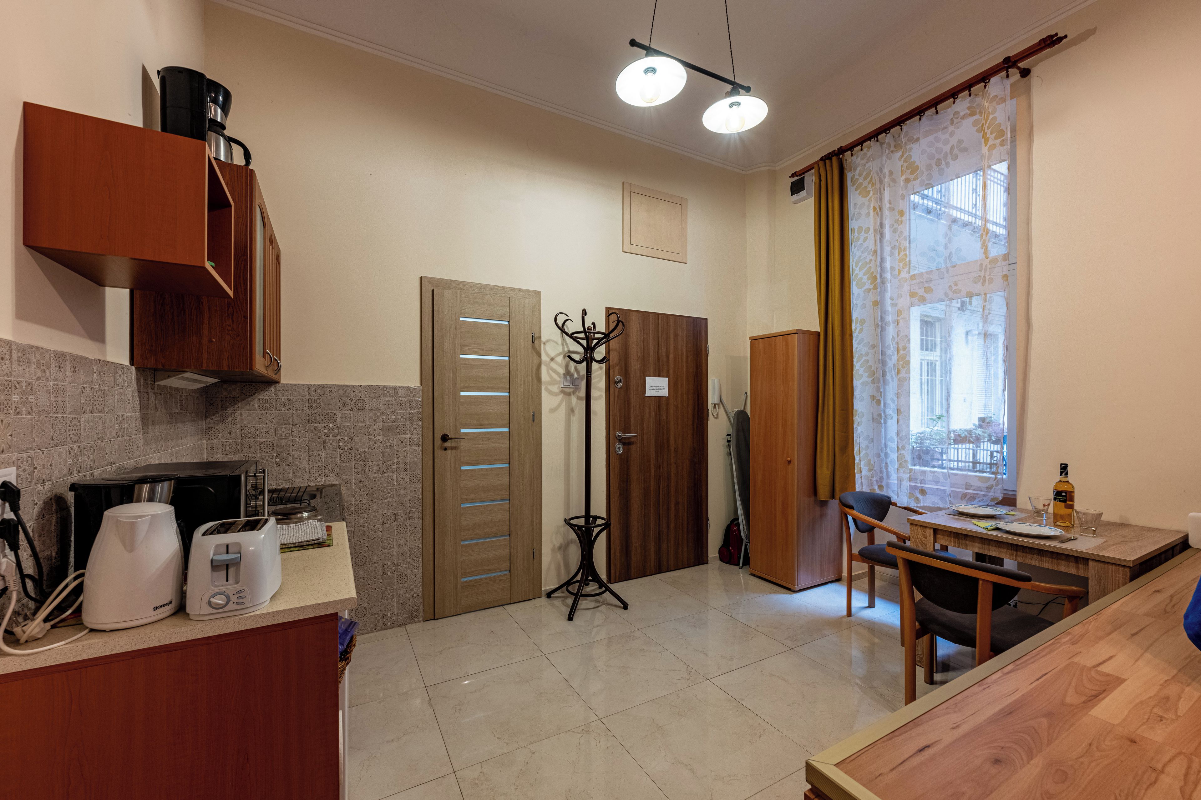 A kitchen with a toaster, a coffee maker, and a dining area with a table and chairs.