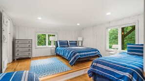 A bedroom with two beds, a dresser, a window, and a view of greenery. - Updated Montauk retreat with breathtaking ocean views and effortless... (Montauk)