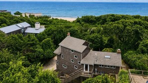 A multi-story house surrounded by dense greenery with a view of the ocean. - Updated Montauk retreat with breathtaking ocean views and effortless... (Montauk)