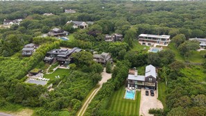An aerial view of a residential area with multiple houses surrounded by dense greenery. - Updated Montauk retreat with breathtaking ocean views and effortless... (Montauk)