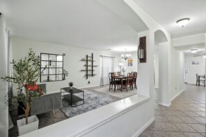 A spacious living area with a dining table, chairs, a sofa, and a coffee table.