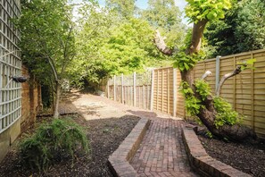 A narrow brick pathway flanked by a wooden fence and dense foliage. - 4 Bedroom House With 2 Bathrooms Near Town Centre (Northampton)