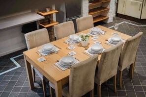 A dining table set for six with white plates, glasses, and cutlery, surrounded by beige chairs. - 4 Bedroom House With 2 Bathrooms Near Town Centre (Northampton)