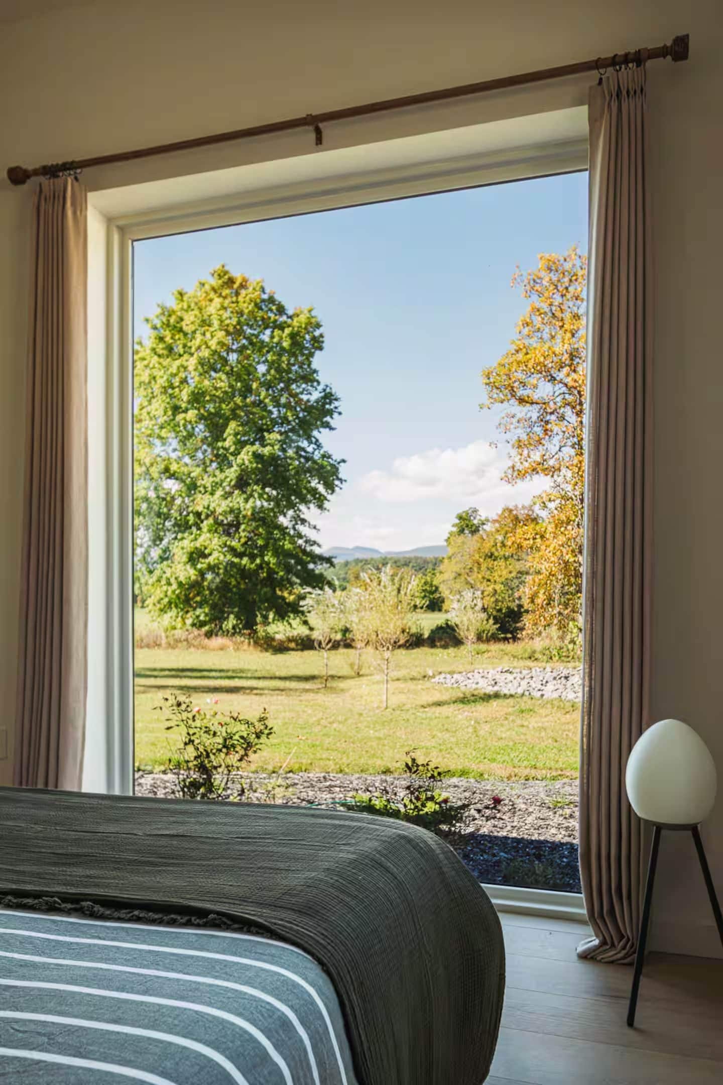 Ein Schlafzimmer mit großem Fenster, einem Bett und einem Sessel.