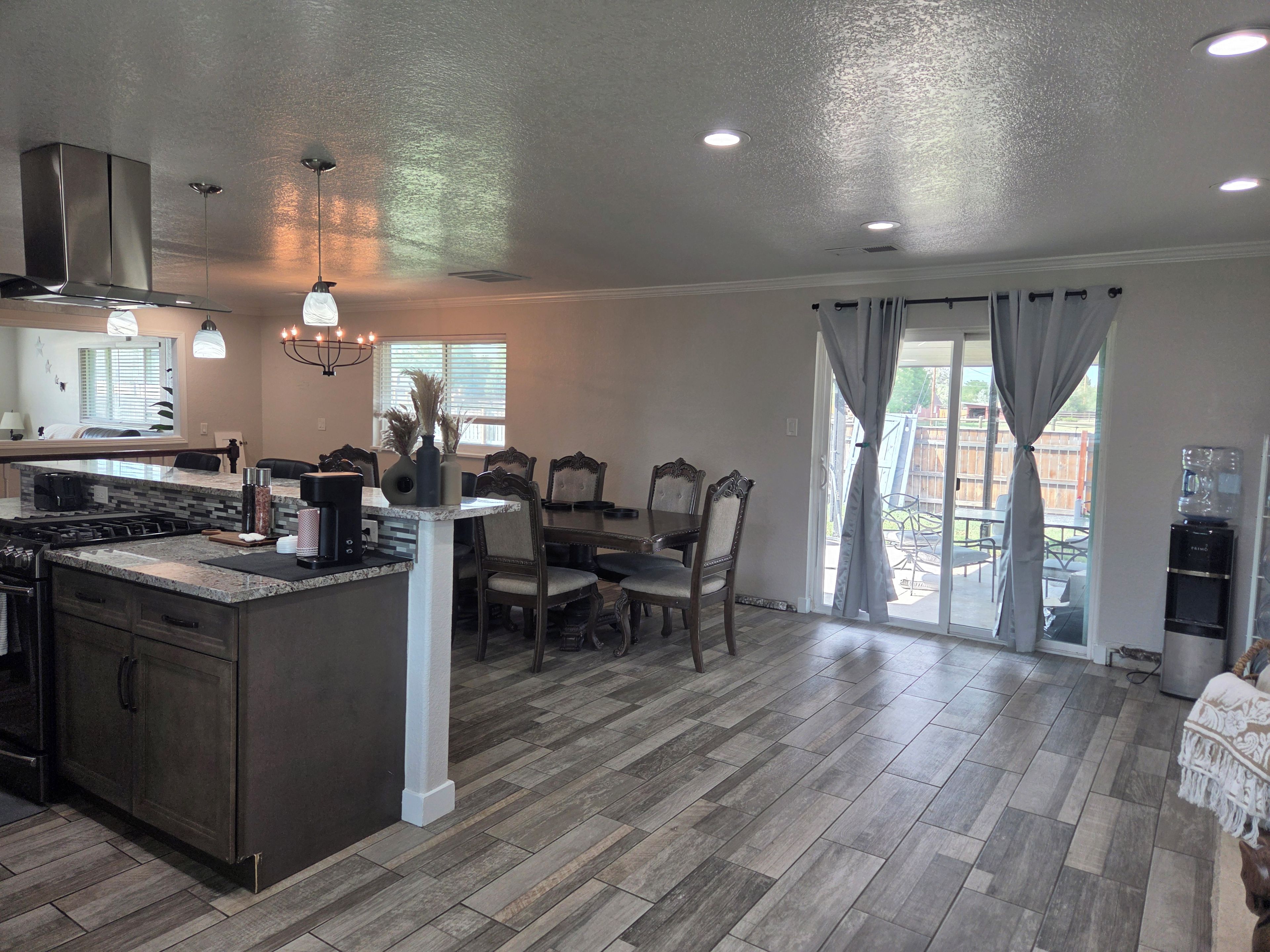 A spacious kitchen with a central island, dining area with chairs, and a sliding glass door to the outdoors.