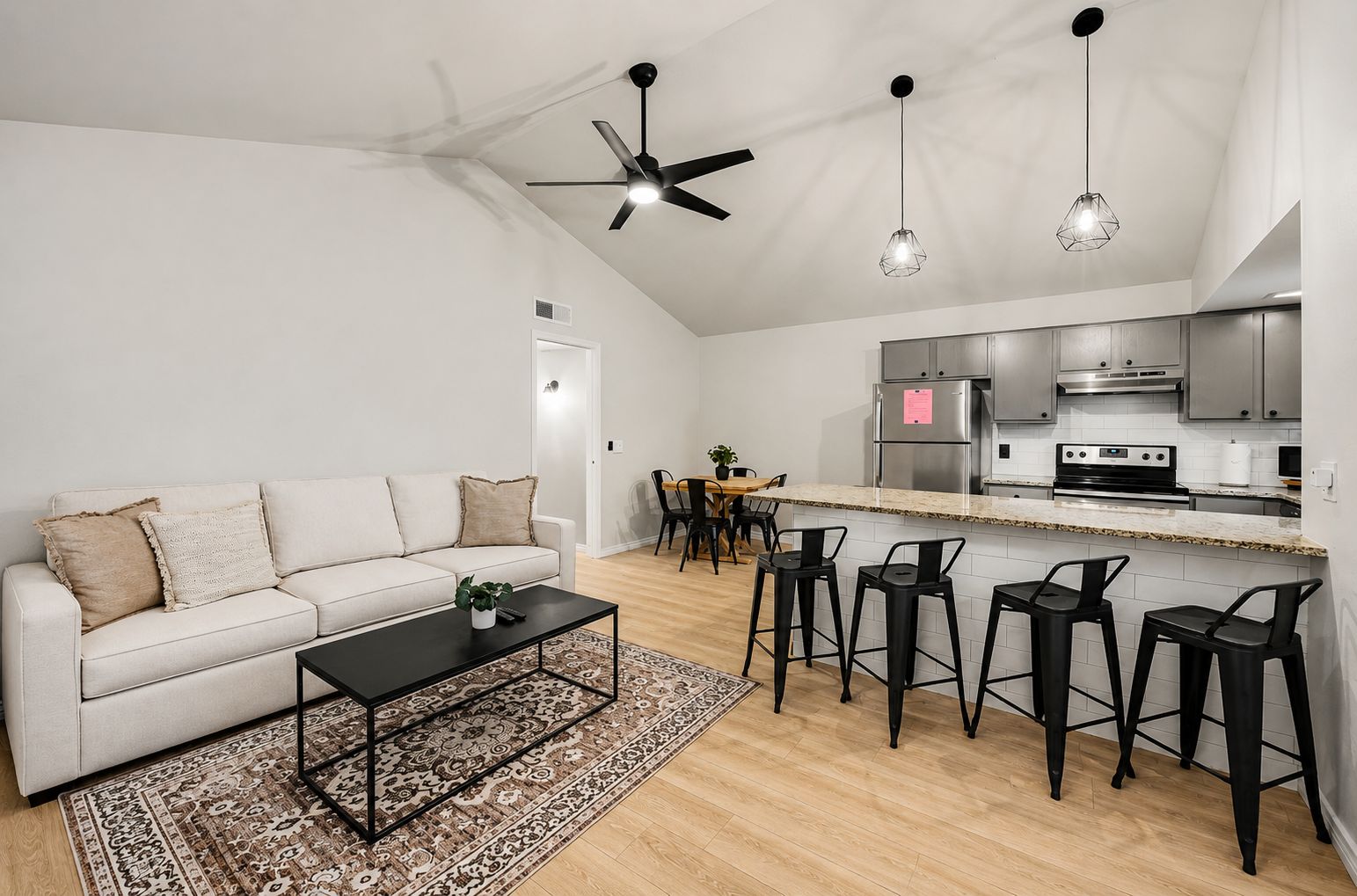 Un salon moderne avec un canapé, une table basse et un coin repas avec des chaises.