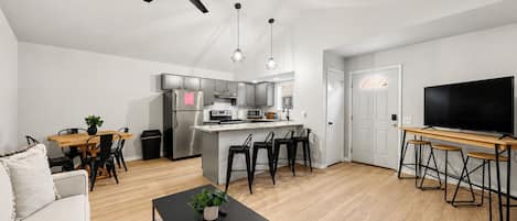 Un apartamento moderno con cocina, comedor, sala de estar y televisor.