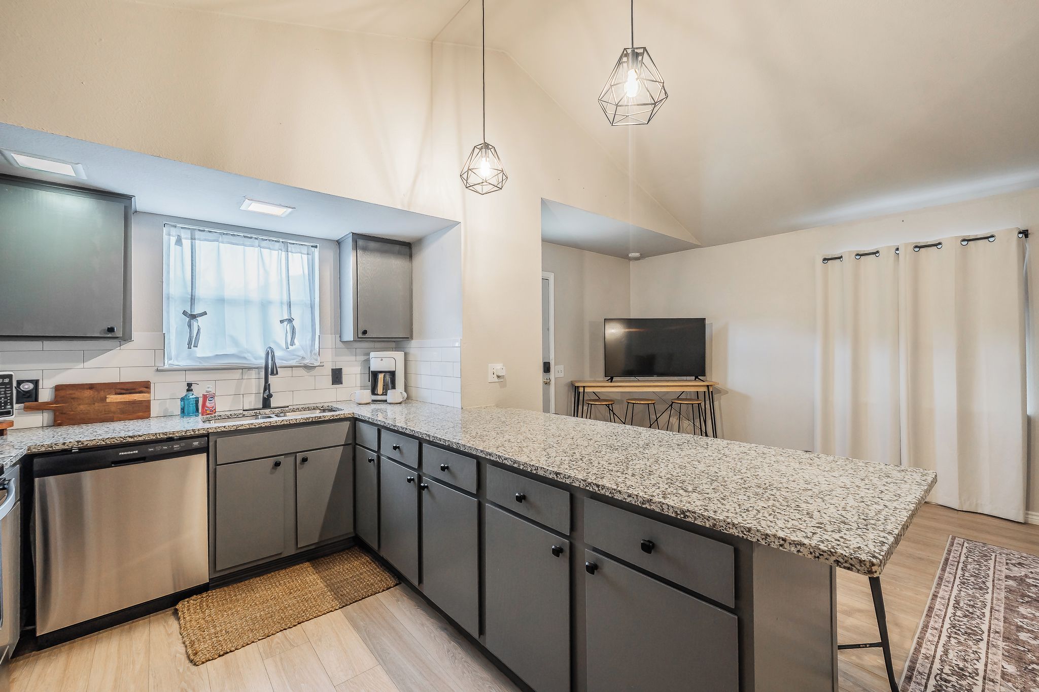 A modern kitchen with granite countertops, stainless steel appliances, and pendant lighting.