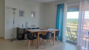 Un coin repas comprenant une table et des chaises, un petit meuble et un lampadaire.