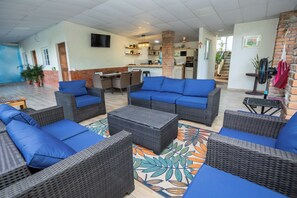 A spacious indoor area with wicker furniture and a kitchen in the background. - Bosq Retreat, Private Pool 5min to  Surf city El Salvador (La Libertad)