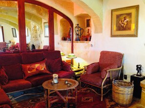Ein gemütliches Wohnzimmer mit roter Polstermöbeln, einem kleinen runden Tisch mit Kerze und einem Korbwannenkorb.