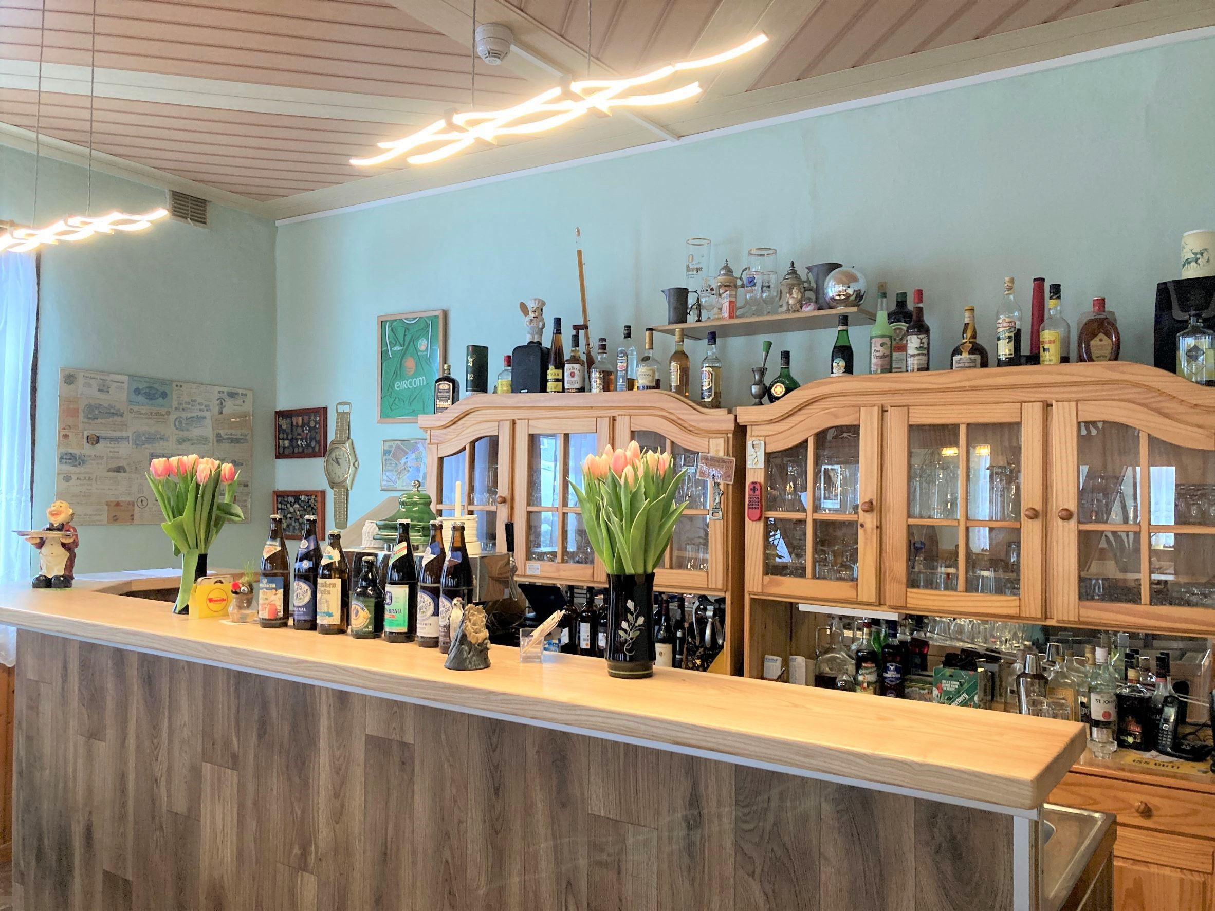 Eine Bar mit Holzausstattung, Flaschen und Tulpen auf der Theke.