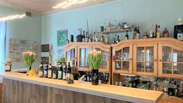 A bar area with wooden cabinets, bottles, and tulips on the counter.