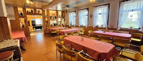 Un restaurante con paredes de madera y mesas cubiertas con manteles rosas.