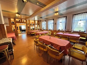 A restaurant with wooden walls and tables covered with pink tablecloths. - Hotel Zur Henne (Suhl)