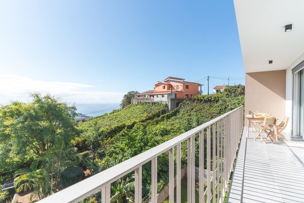 Un balcone con vista su un pendio collinare e un edificio in lontananza.
