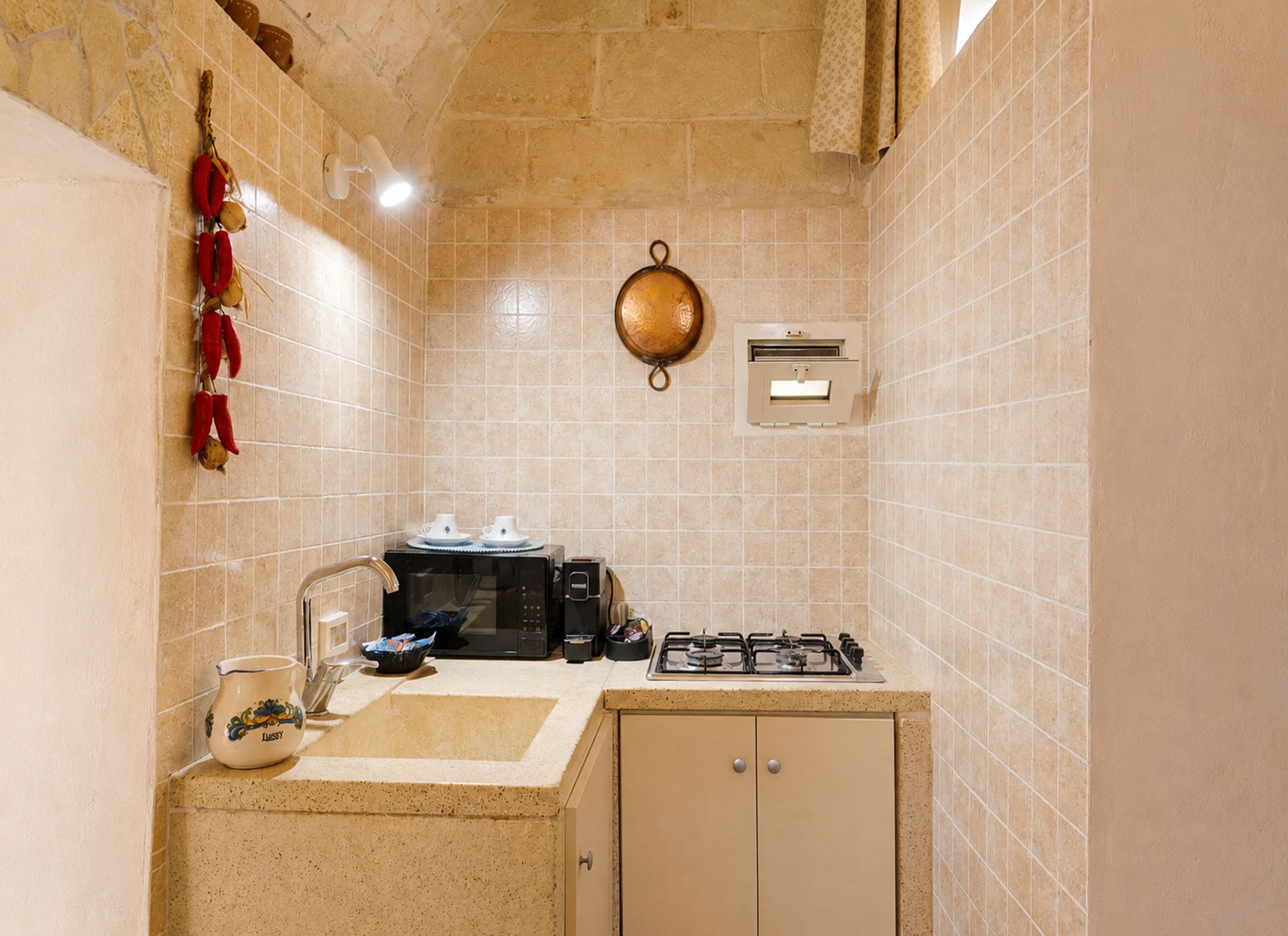 A compact kitchen with a gas stove, a coffee machine, and a microwave.