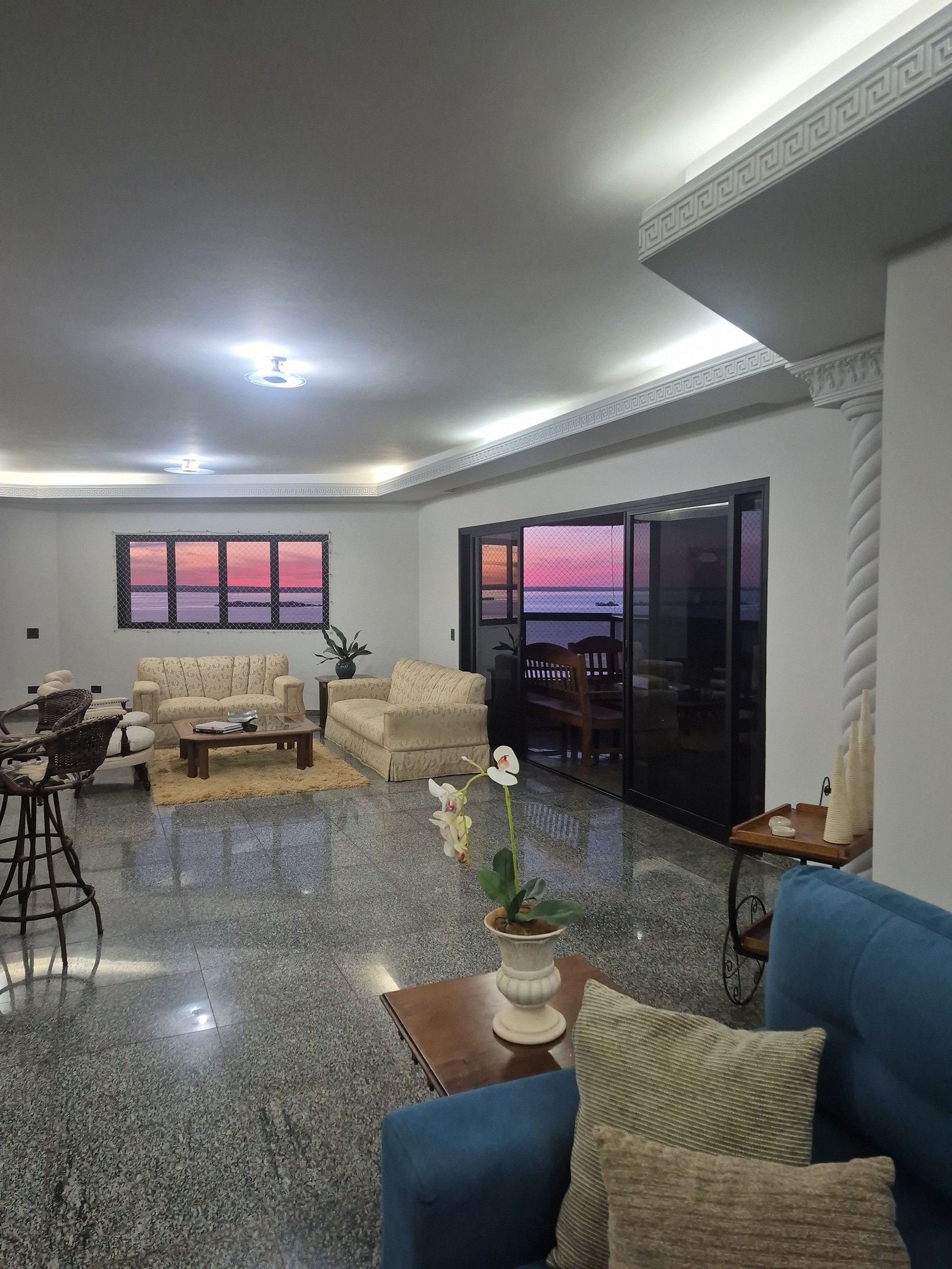 A spacious living room with a large window, a blue sofa, a beige sofa, and a coffee table.