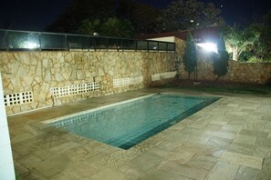 A swimming pool with stone walls and a tiled deck.