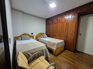 Un dormitorio con dos camas individuales, un armario de madera y una puerta.