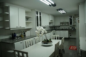 Una cocina moderna con armarios blancos, encimera de granito y una mesa de comedor con sillas.